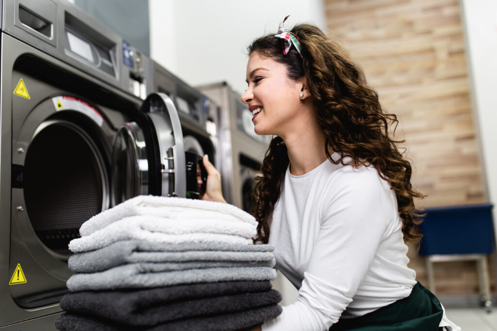 Beautiful female employee working at laundromat shop.