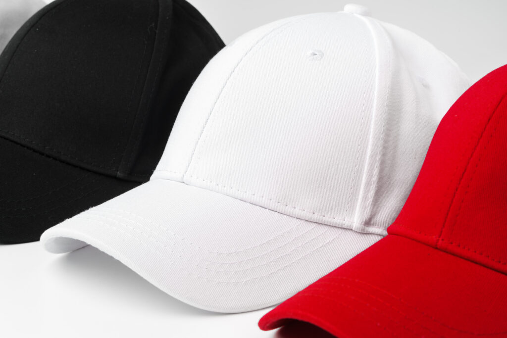 A selection of four baseball caps is neatly arranged in a row, showcasing the colors red, white, and black.